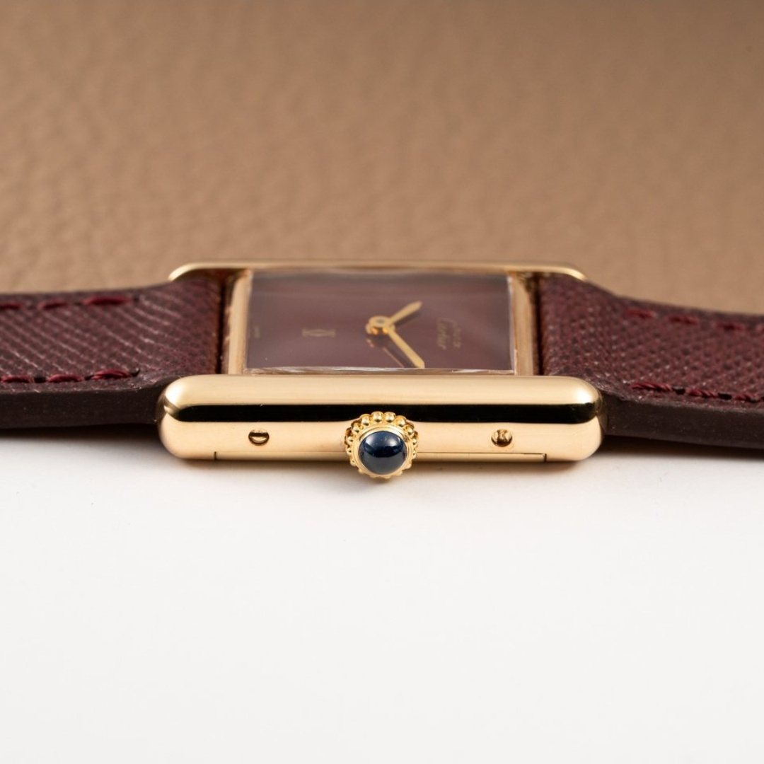 Profile view with the blue cabochon set into the crown, and the case screws visible along the brancard.