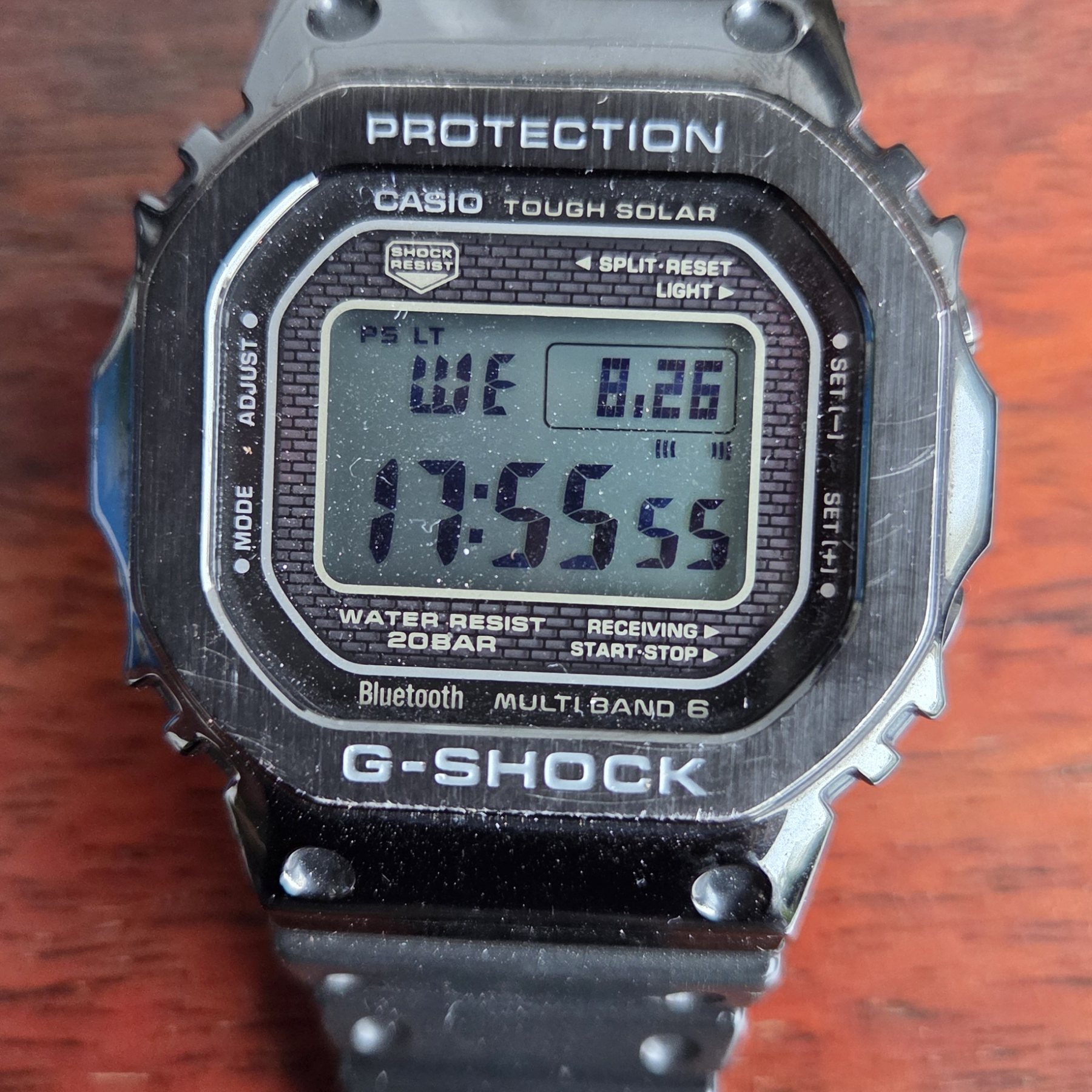 A full-metal Casio G-Shock square with a black finish, its negative LCD showing the time.