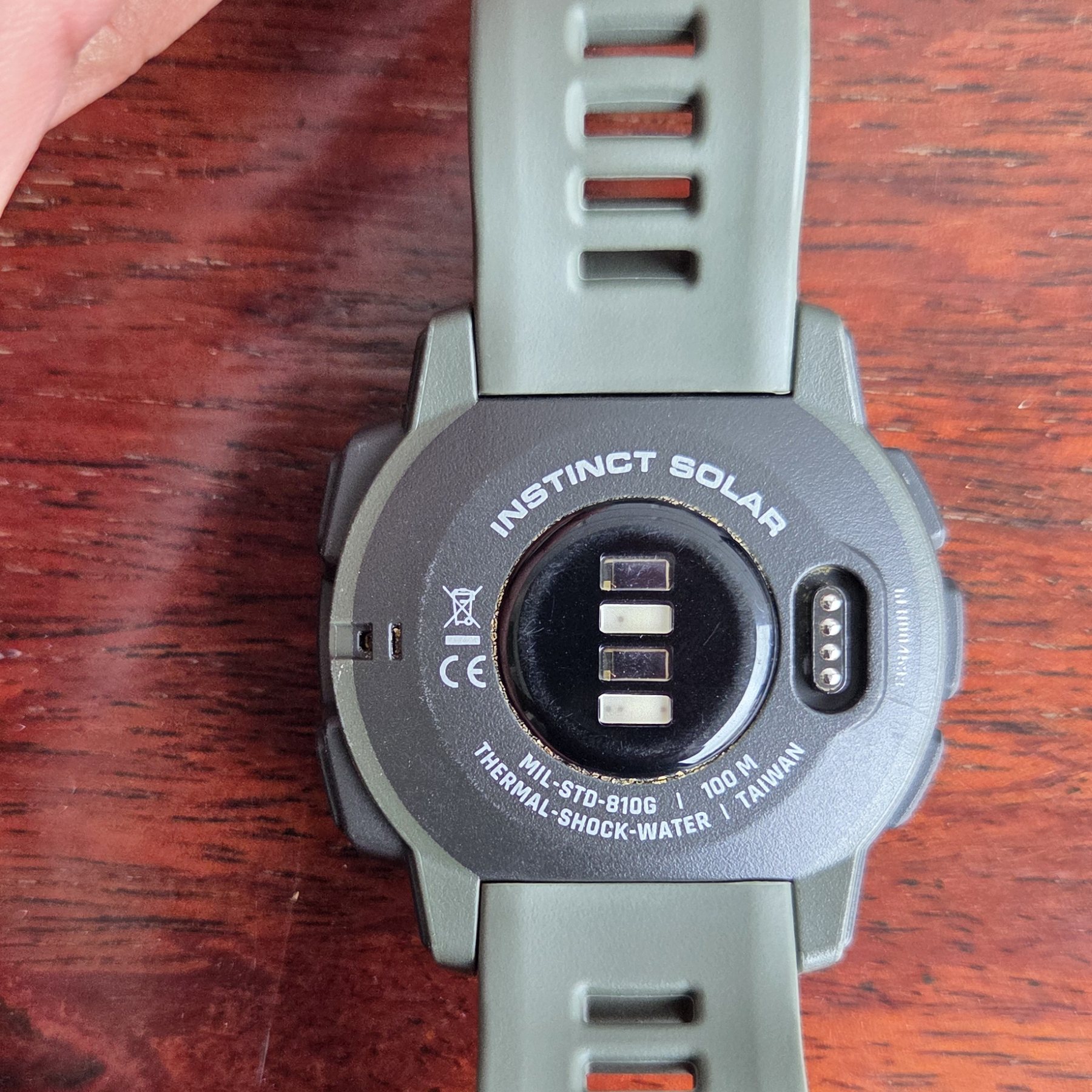 The case back, stamped INSTINCT SOLAR and MIL-STD-810G, with the charging contacts.