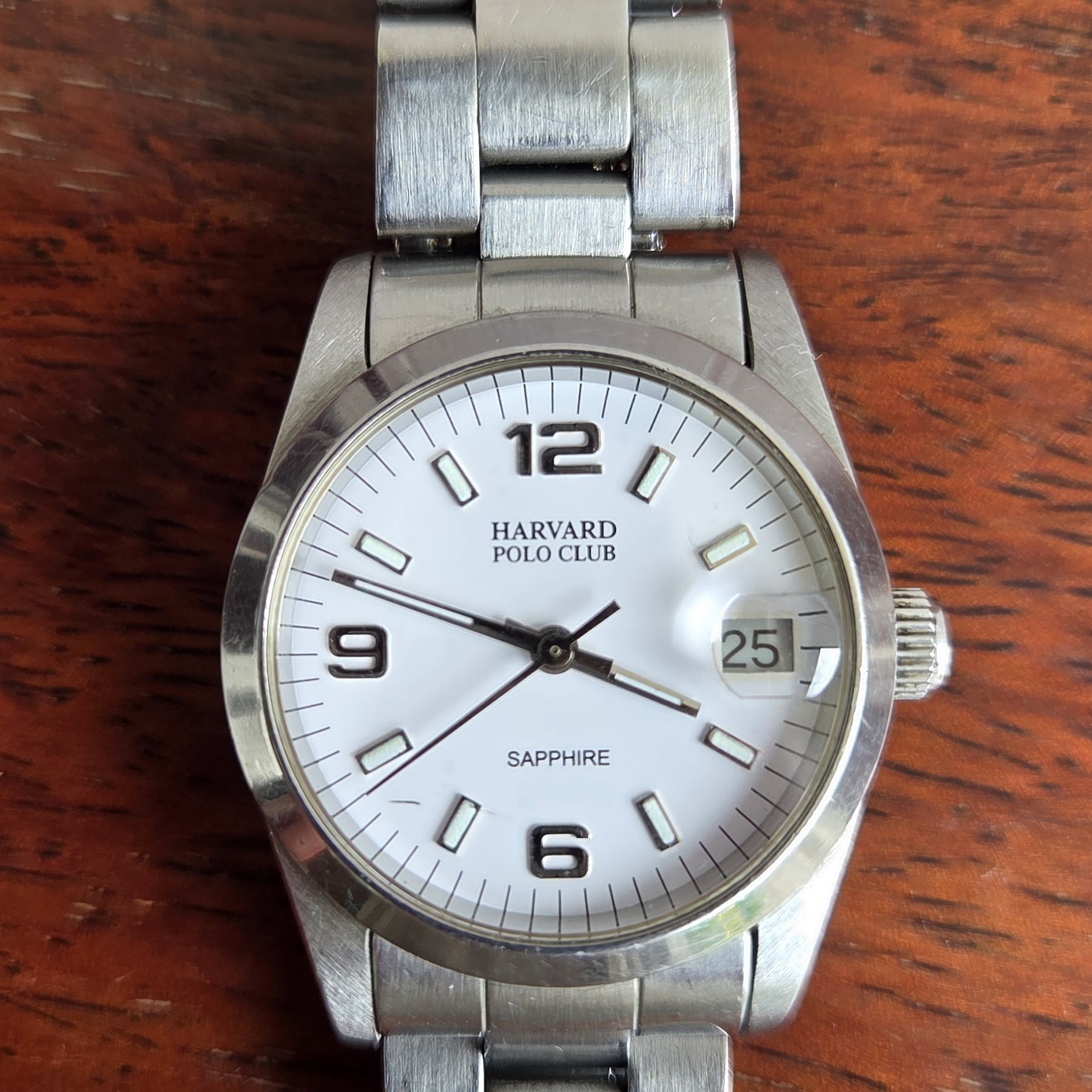 The watch at an angle, the bracelet curving away across a wooden table.