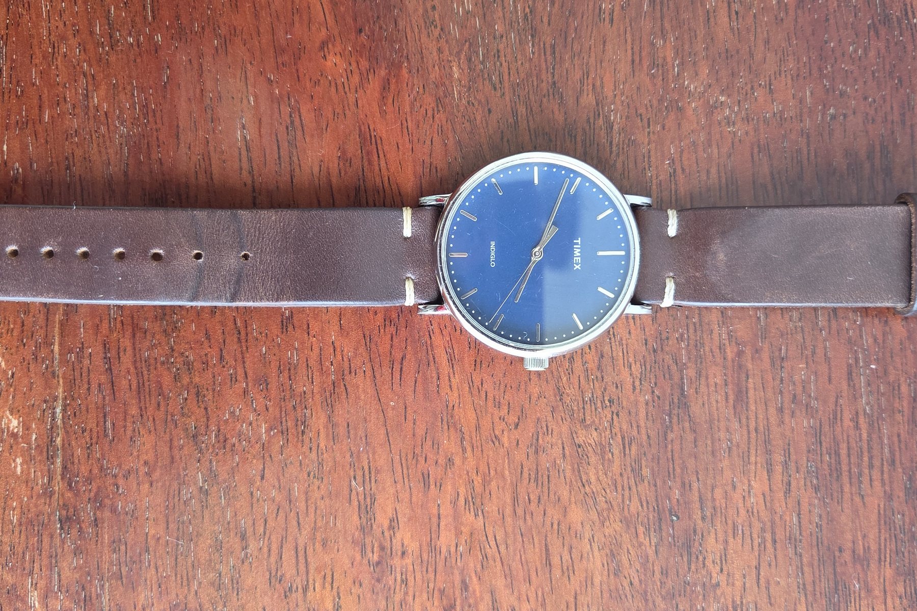The watch laid out flat with the strap extended on a wooden surface.