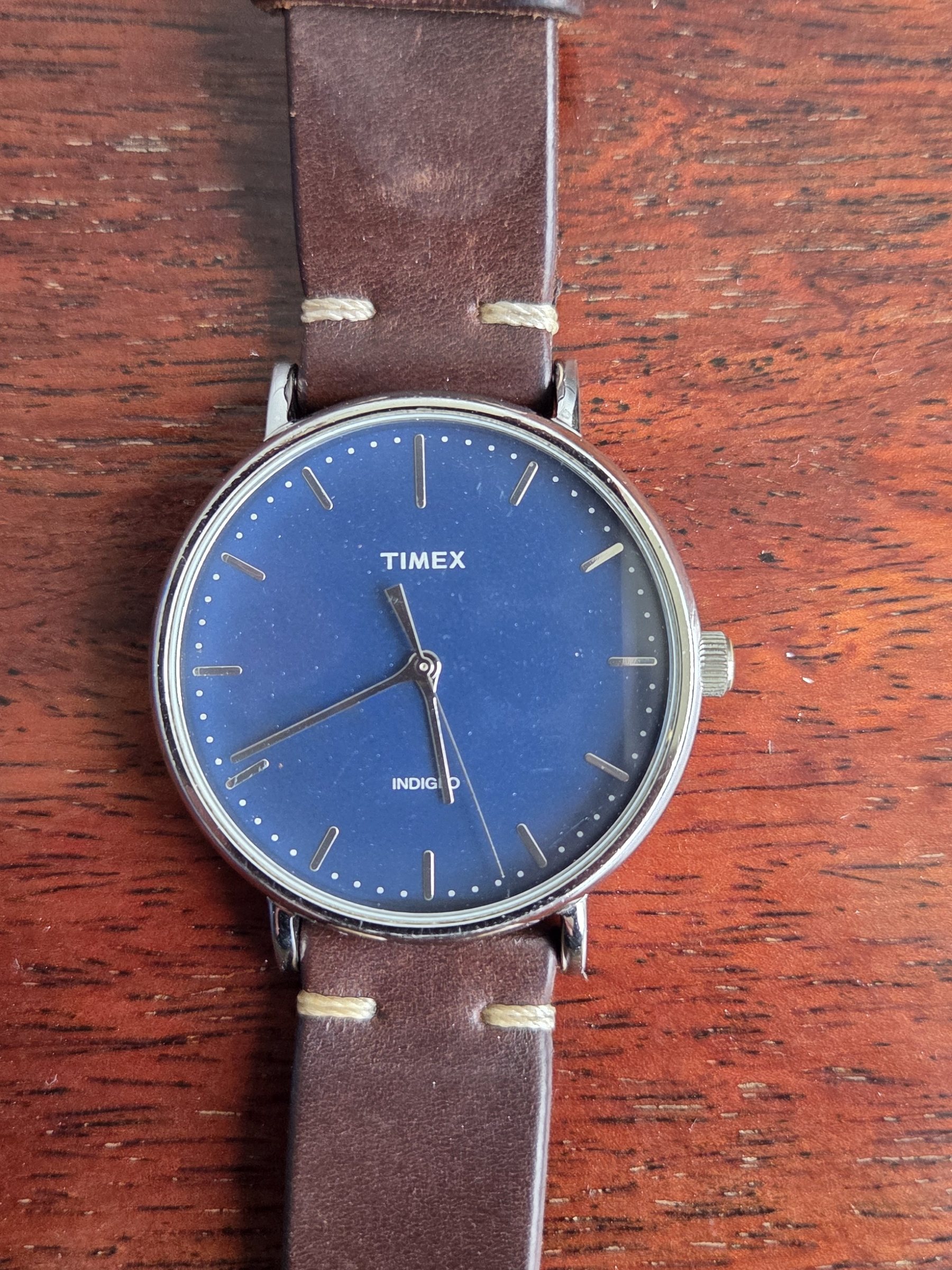 The whole watch with the brown leather strap extended, seen from above.
