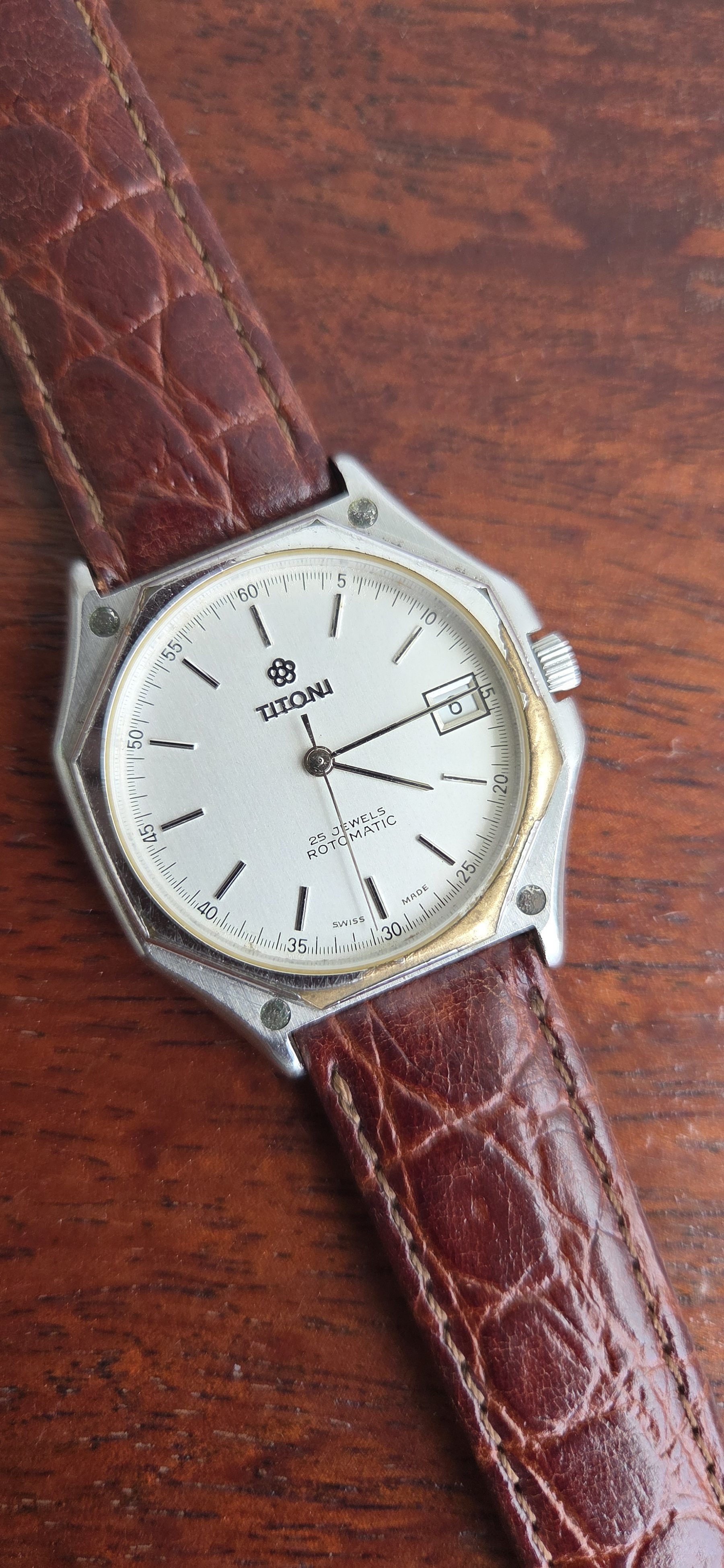 A Titoni wristwatch with a white dial, baton markers and a date window, on a brown alligator strap.