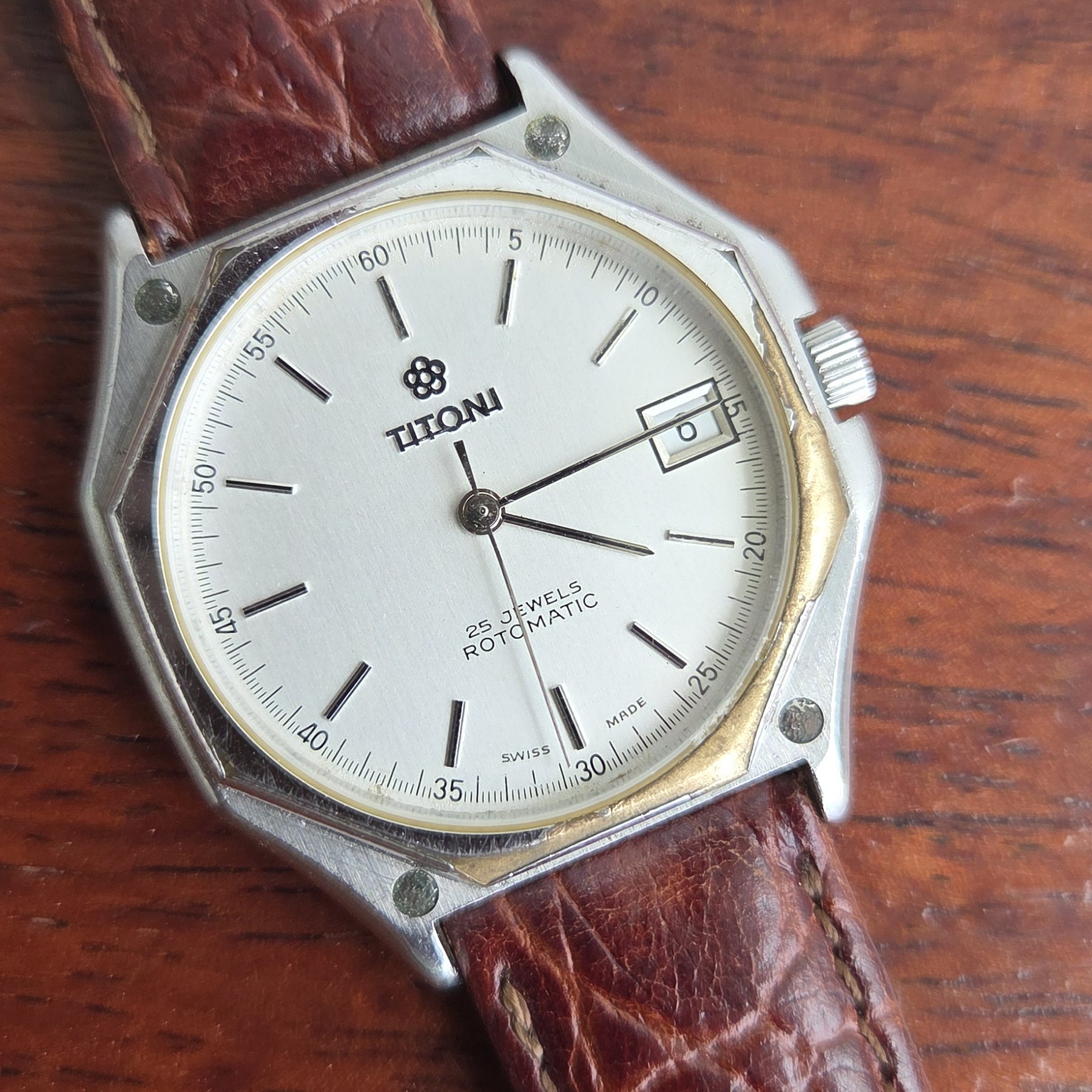 A Titoni wristwatch with a white dial, baton markers and a date window, on a brown alligator strap.