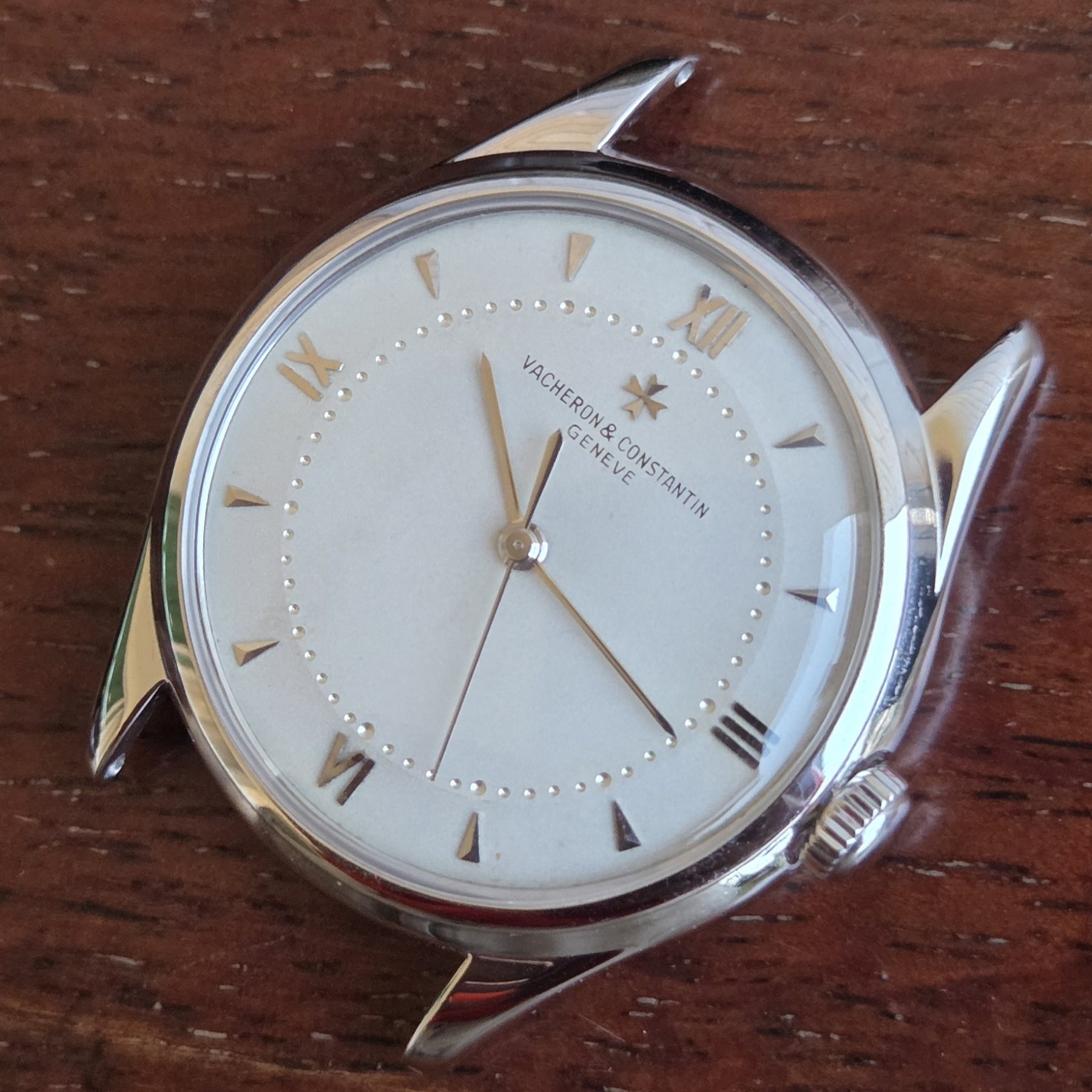 The watch head at a slight angle, light raking across the silvered dial and the polished lugs.