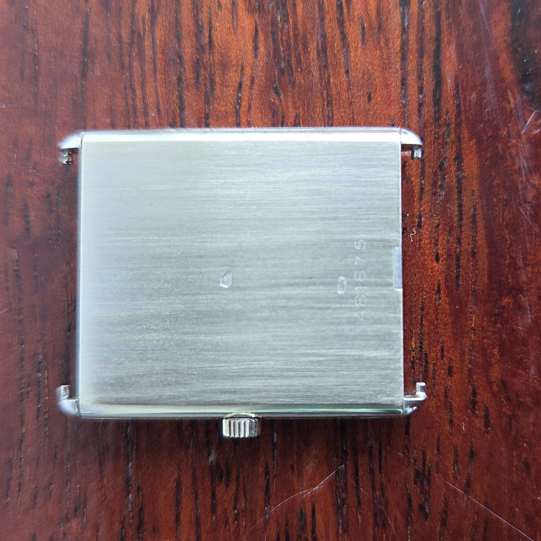The plain brushed rectangular case back, with no engraving on the outside.