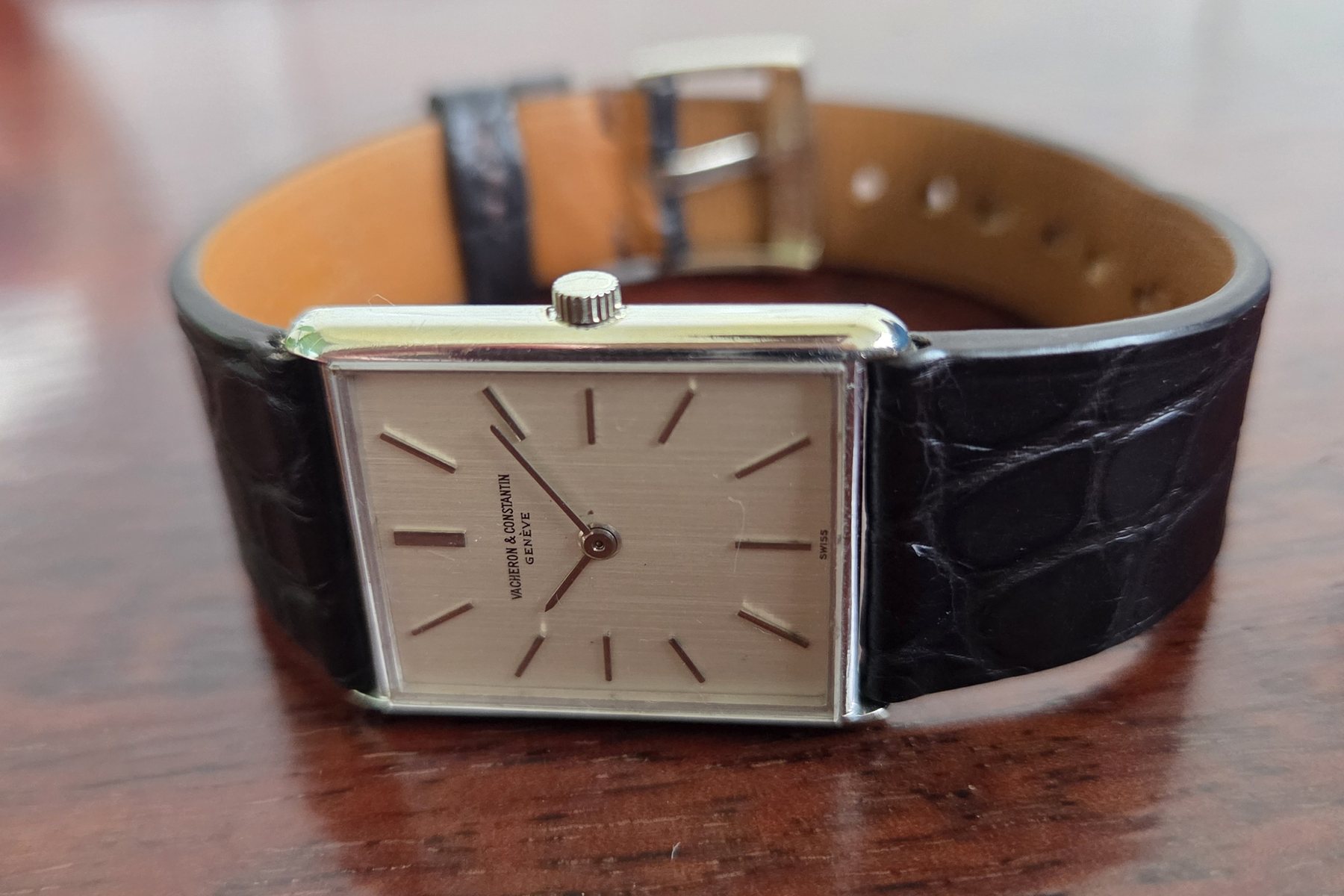 The same watch at a low angle with the strap curled behind it and the signed buckle standing up.