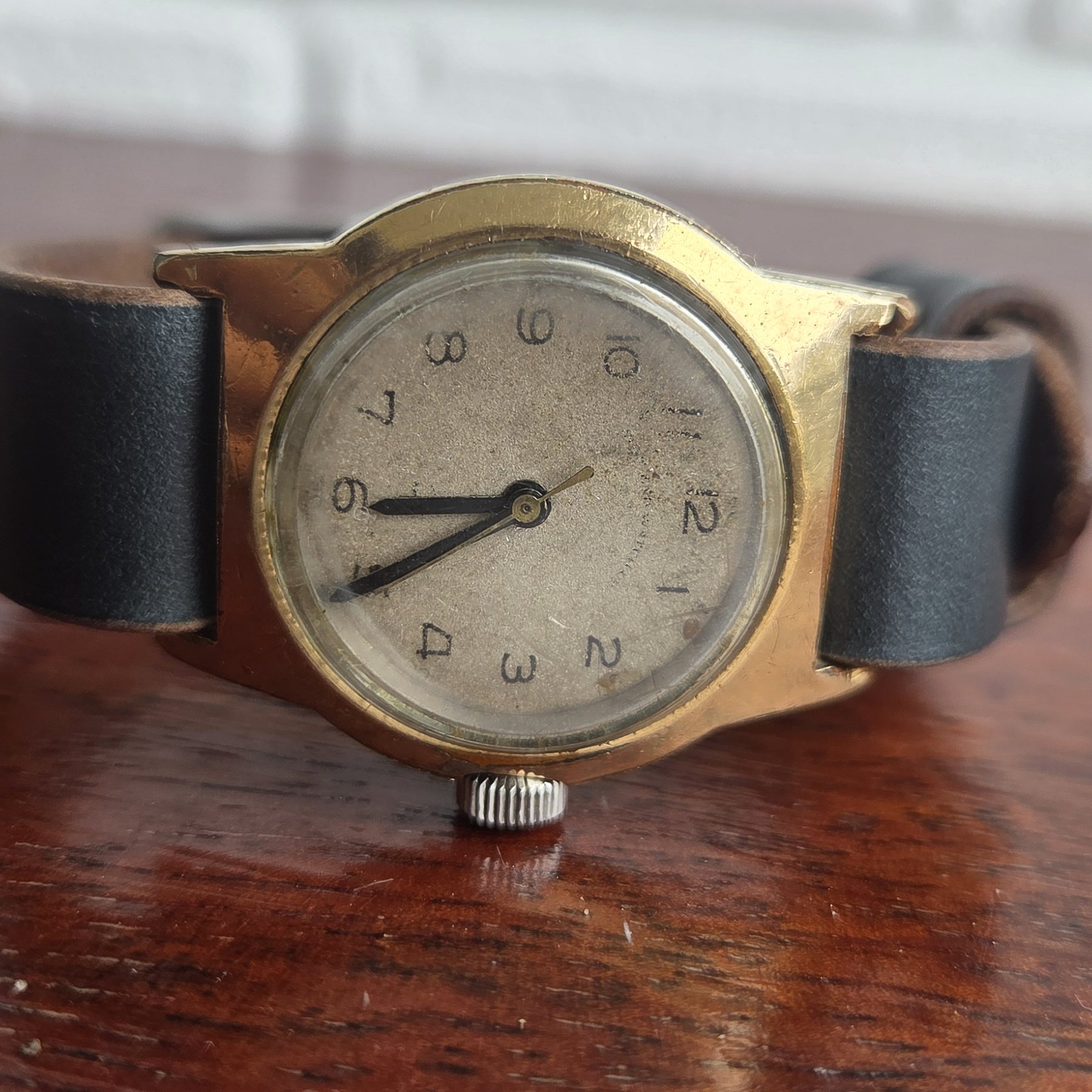 A three-quarter view of the watch on its black leather strap.