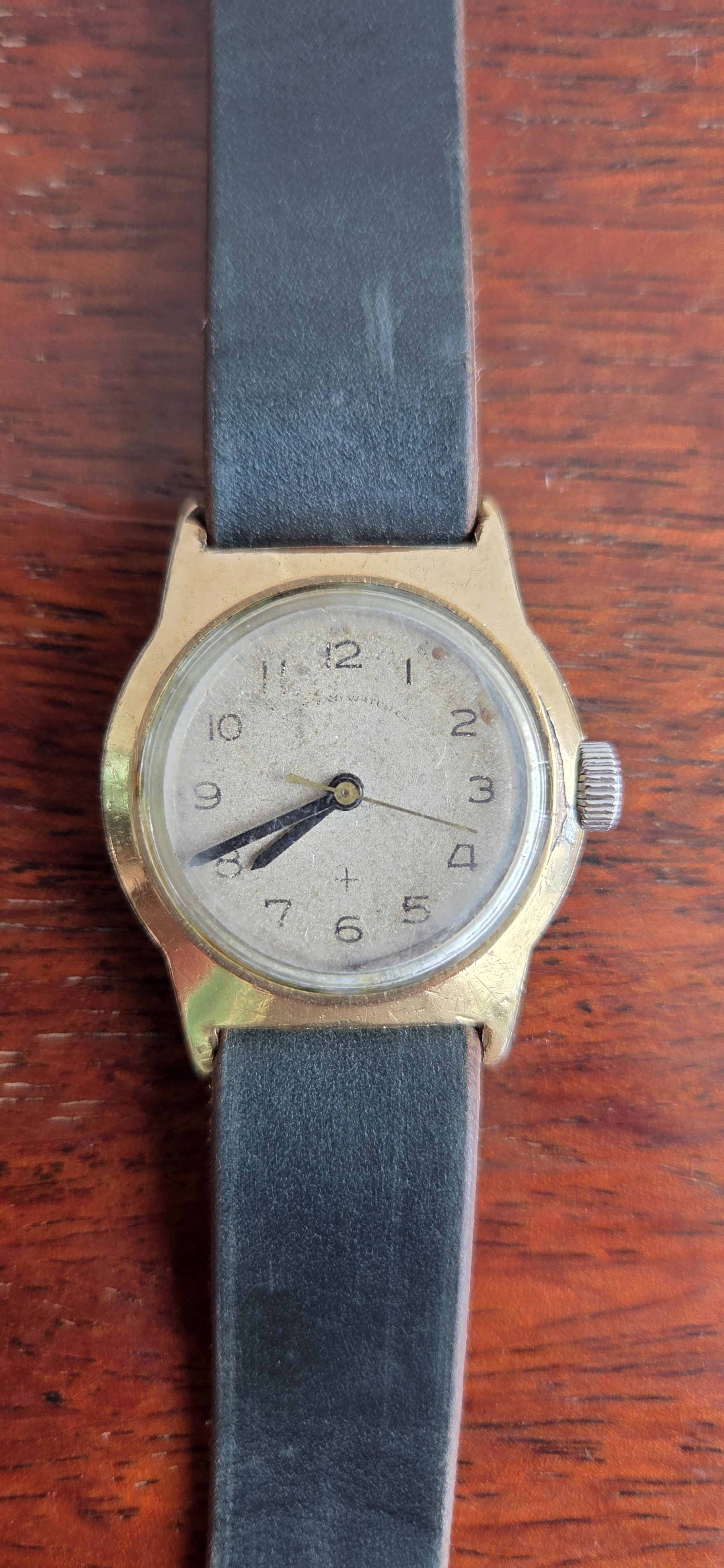 A small vintage West End Watch Co. wristwatch with an aged cream dial and Arabic numerals.
