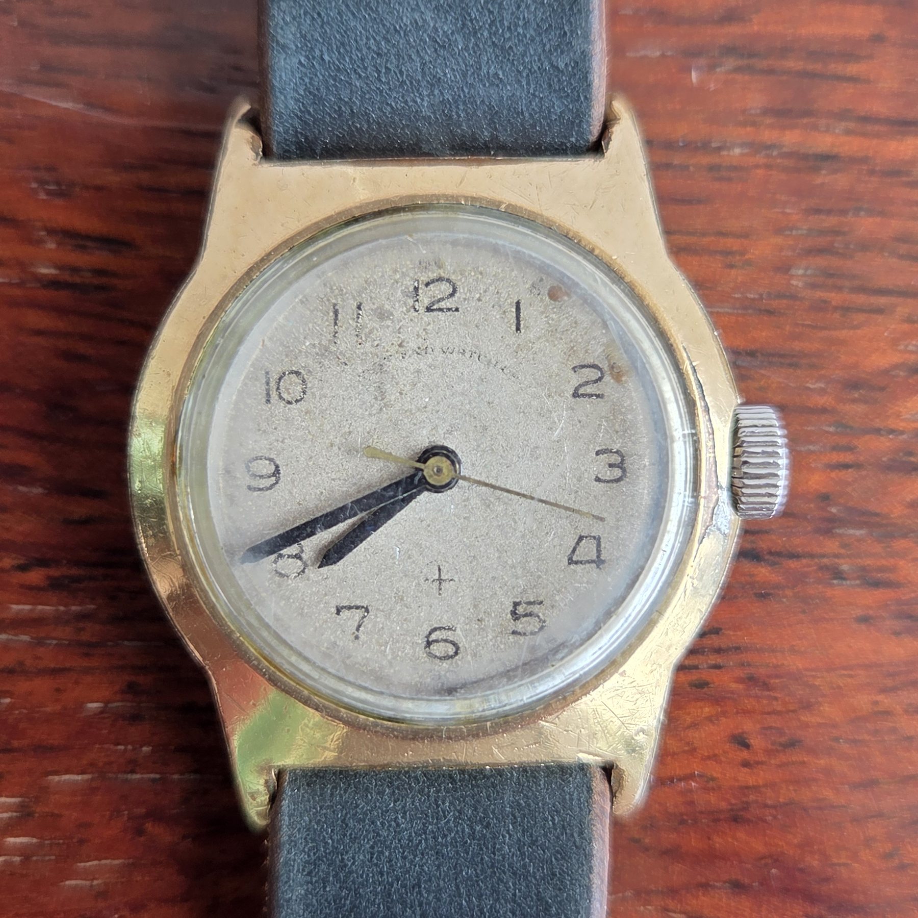 A small vintage West End Watch Co. wristwatch with an aged cream dial and Arabic numerals.